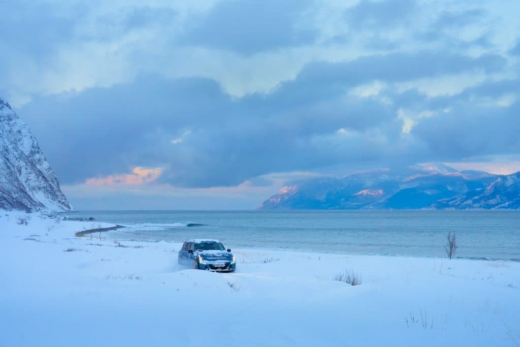 En Kia EV9 kör genom ett snöigt kustlandskap.