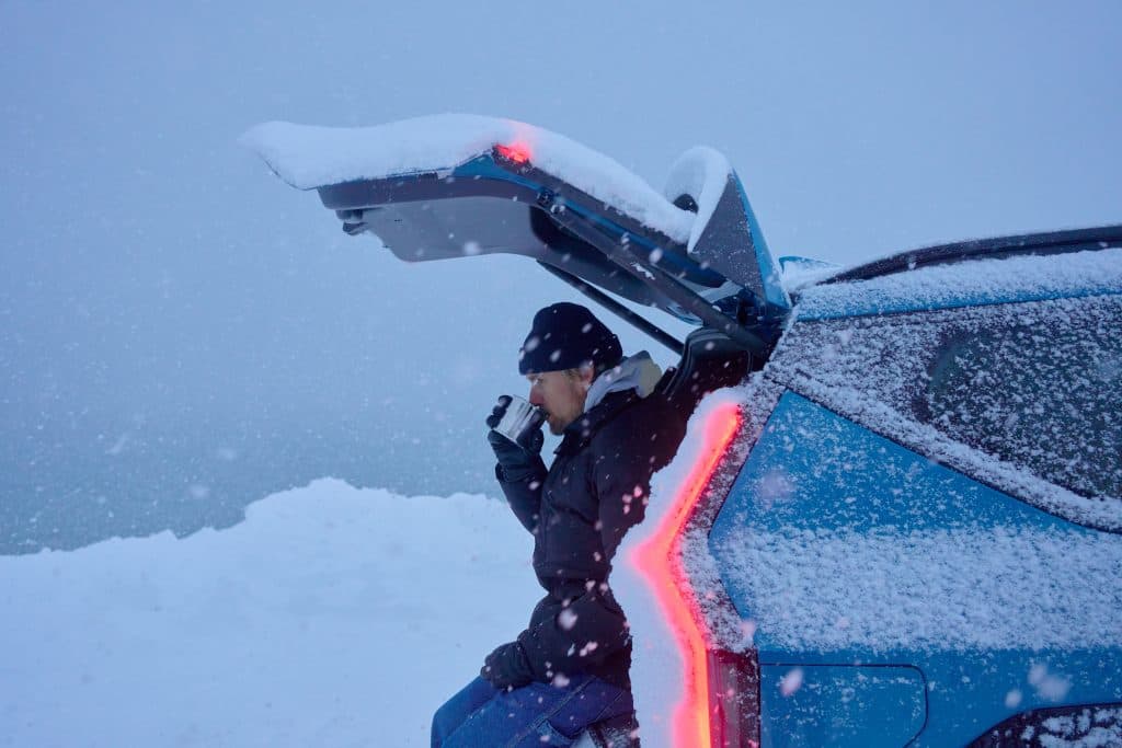Tim Latte sitter i bak på sin bil och dricker en kopp kaffe i snöväder.