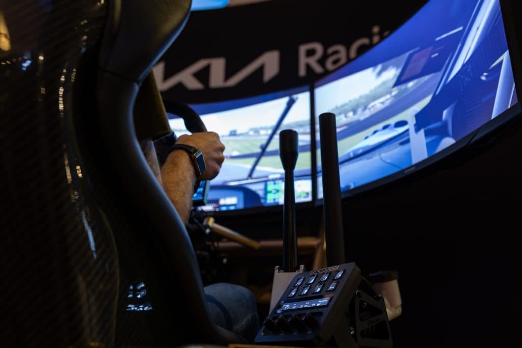 En racingsimulator med tre skärmar sedd snett bakifrån.